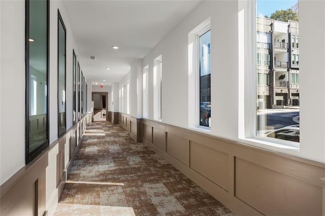 hall with a decorative wall, recessed lighting, visible vents, and a wainscoted wall