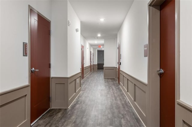 corridor with dark wood finished floors and a wainscoted wall