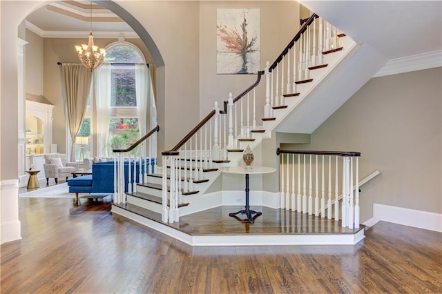 452 Brushstroke Ct SE, Marietta, GA 30067 - stairway with arched walkways, a towering ceiling, wood finished floors, a chandelier, and ornamental molding