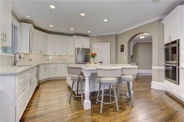 452 Brushstroke Ct SE, Marietta, GA 30067 - kitchen featuring stainless steel appliances, a sink, crown molding, a kitchen bar, and arched walkways
