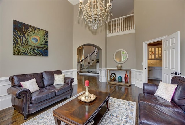 452 Brushstroke Ct SE, Marietta, GA 30067 - living room featuring arched walkways, a high ceiling, a chandelier, wood finished floors, and a wainscoted wall