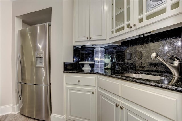 452 Brushstroke Ct SE, Marietta, GA 30067 - kitchen featuring stainless steel fridge, a sink, tasteful backsplash, dark stone countertops, and glass insert cabinets