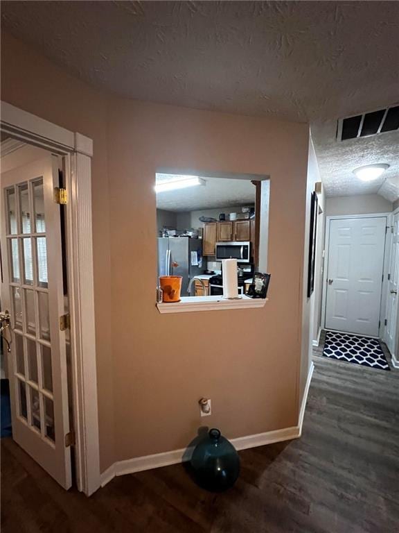 corridor featuring a textured ceiling and dark wood-type flooring