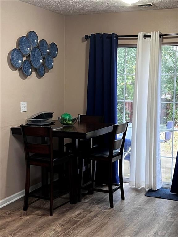 dining space with a textured ceiling, a healthy amount of sunlight, and hardwood / wood-style flooring