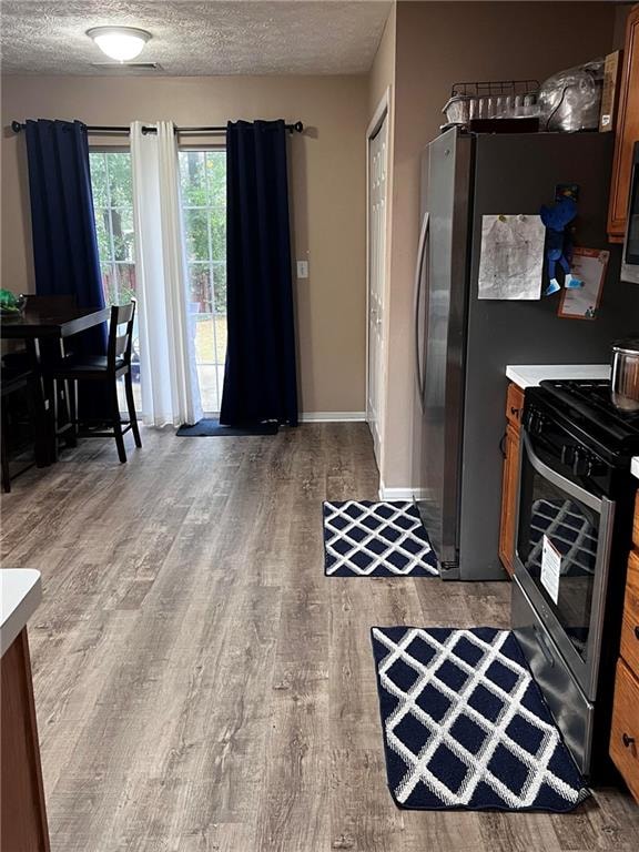 kitchen with a textured ceiling, appliances with stainless steel finishes, and hardwood / wood-style floors