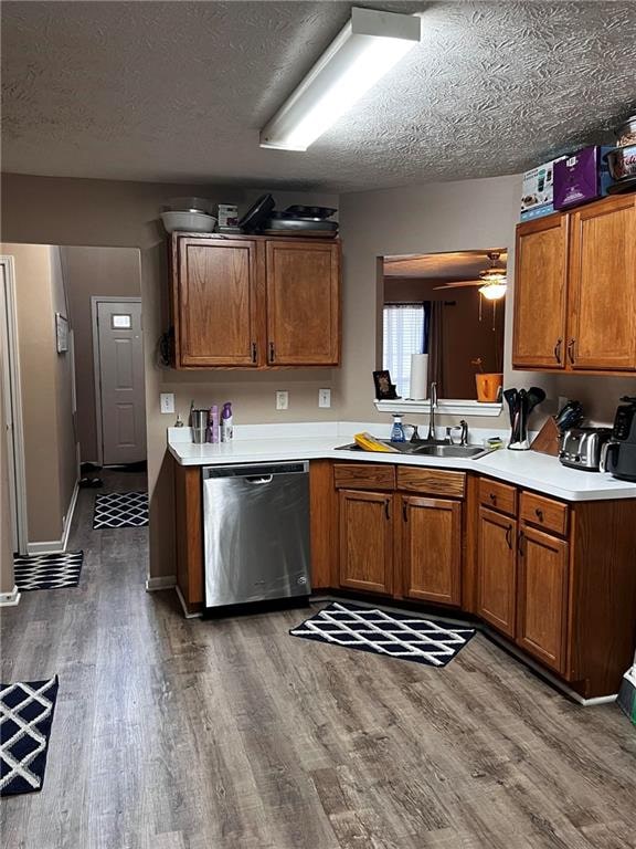 kitchen with ceiling fan, sink, stainless steel dishwasher, a textured ceiling, and dark wood-type flooring