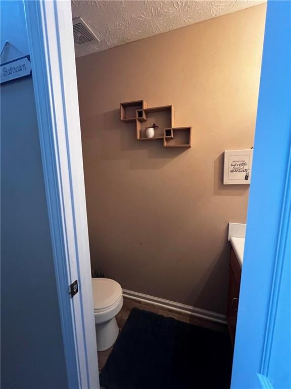 bathroom with a textured ceiling, vanity, and toilet