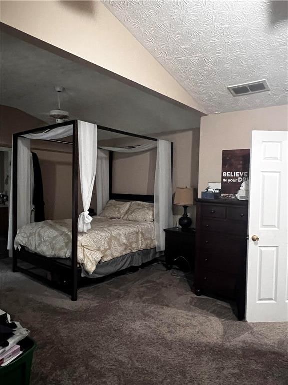 bedroom featuring vaulted ceiling, a textured ceiling, and carpet flooring