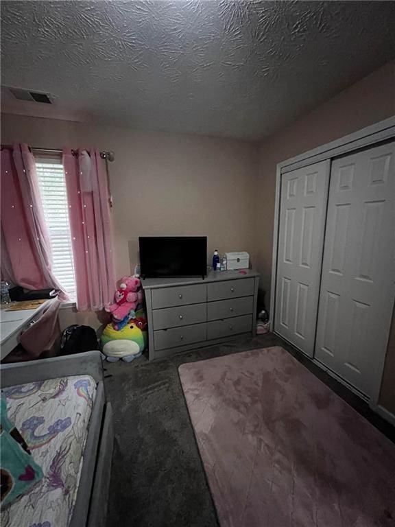 carpeted bedroom with a textured ceiling and a closet