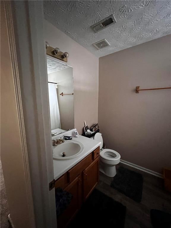 bathroom featuring curtained shower, vanity, a textured ceiling, wood-type flooring, and toilet