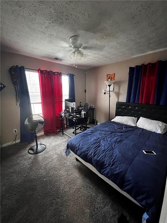 bedroom featuring ceiling fan, a textured ceiling, and carpet floors