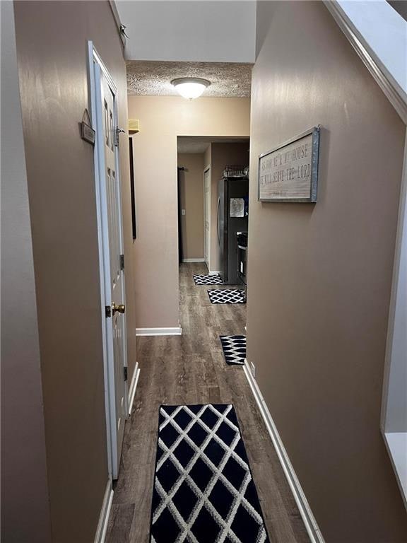 hall with a textured ceiling and dark hardwood / wood-style floors