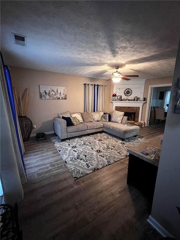 living room with ceiling fan, dark hardwood / wood-style floors, and a textured ceiling