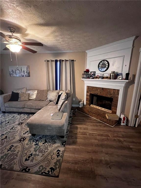 living room featuring ceiling fan, hardwood / wood-style flooring, a fireplace, and a textured ceiling