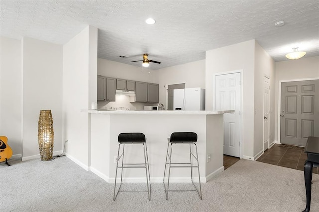 554 Rendevous Rd, Acworth, GA 30102 - kitchen with freestanding refrigerator, gray cabinets, dark colored carpet, a kitchen bar, and baseboards