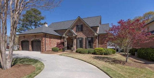 tudor house featuring a garage, brick siding, and concrete driveway