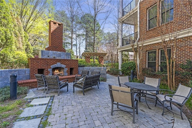 view of patio featuring outdoor dining area, a balcony, and an outdoor living space with a fireplace