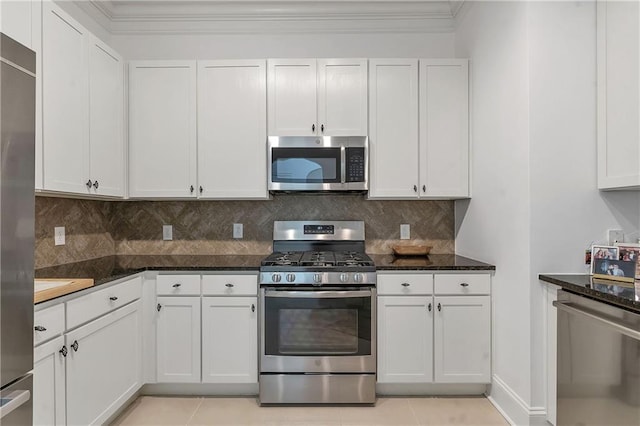 kitchen with ornamental molding, appliances with stainless steel finishes, white cabinetry, backsplash, and light tile patterned flooring