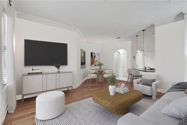 living area with ornamental molding, baseboards, arched walkways, and wood finished floors