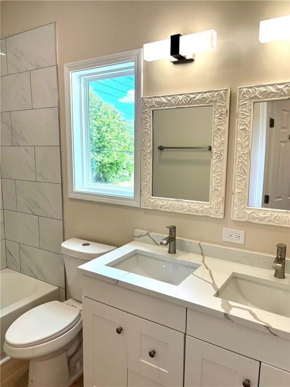 full bathroom featuring vanity, tiled shower / bath, and toilet