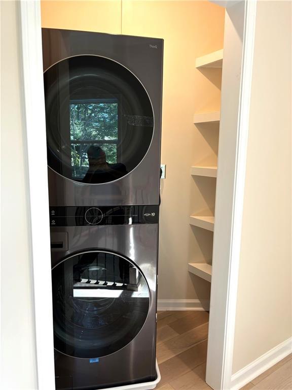 washroom with built in shelves and stacked washer and dryer