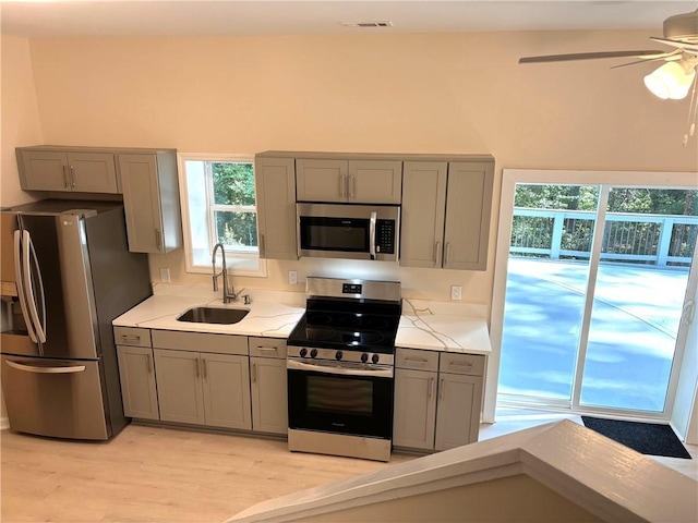 kitchen featuring sink, gray cabinetry, ceiling fan, stainless steel appliances, and light hardwood / wood-style floors