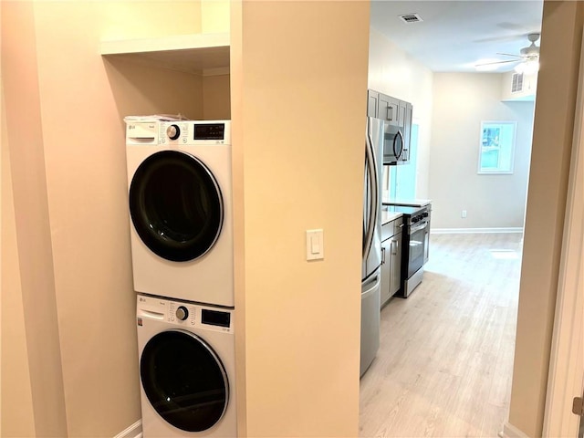 laundry room featuring stacked washer and clothes dryer, ceiling fan, and light wood-type flooring