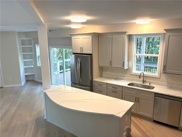 kitchen featuring light stone counters, appliances with stainless steel finishes, gray cabinets, and sink