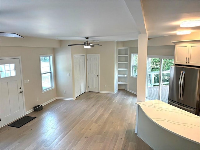 entrance foyer with ceiling fan, a wealth of natural light, and light wood-type flooring