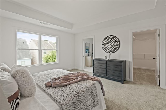 carpeted bedroom featuring a walk in closet, a tray ceiling, and a closet