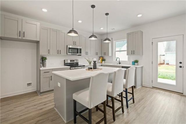 kitchen featuring light hardwood / wood-style flooring, a wealth of natural light, stainless steel appliances, and a kitchen island