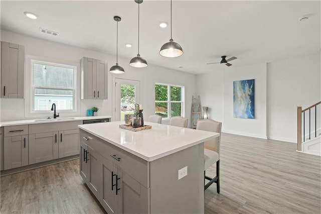 kitchen featuring gray cabinetry, light hardwood / wood-style flooring, a kitchen island, and ceiling fan