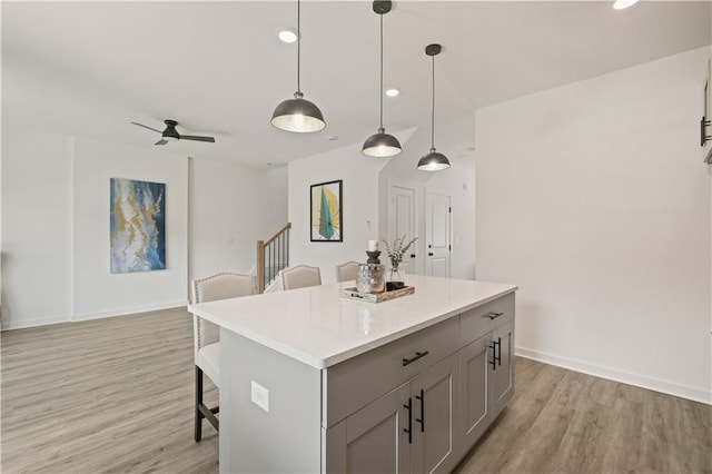 kitchen with ceiling fan, gray cabinetry, pendant lighting, and light hardwood / wood-style floors