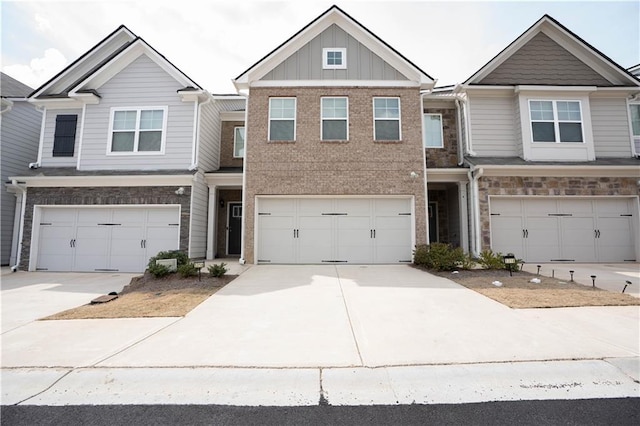 townhome / multi-family property with stone siding, an attached garage, driveway, and board and batten siding