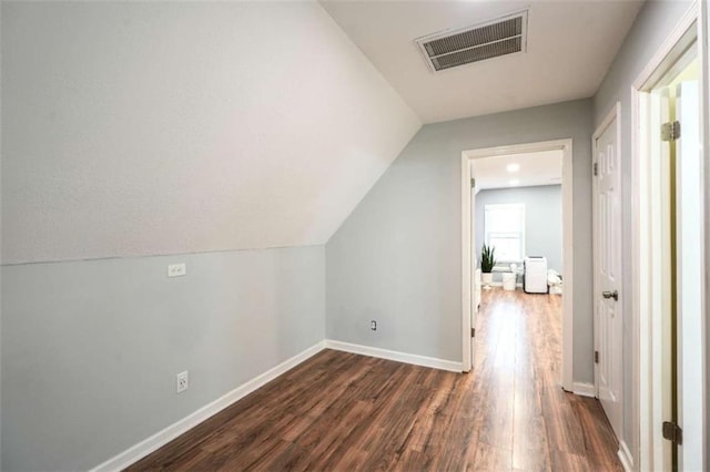 additional living space with vaulted ceiling and dark hardwood / wood-style flooring