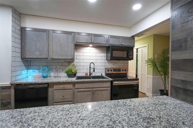 kitchen featuring light stone countertops, sink, decorative backsplash, and black appliances