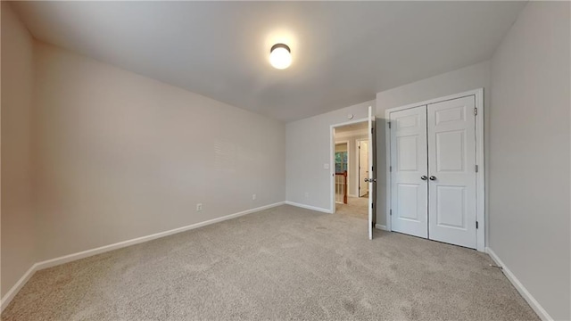 unfurnished bedroom with light colored carpet and a closet