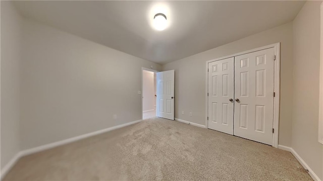 unfurnished bedroom with light colored carpet and a closet