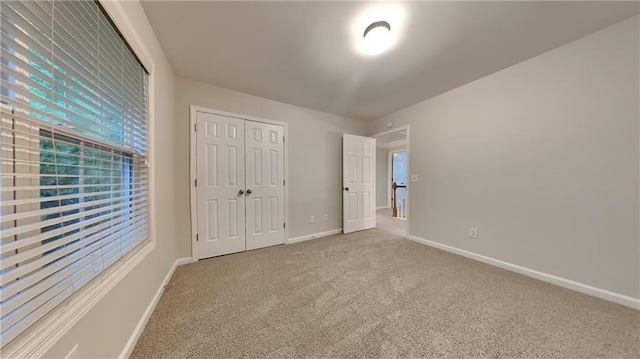 unfurnished bedroom with light colored carpet and a closet