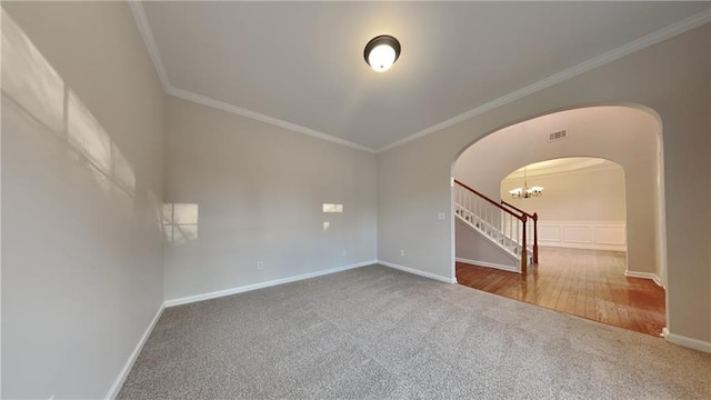 carpeted empty room featuring crown molding and a chandelier