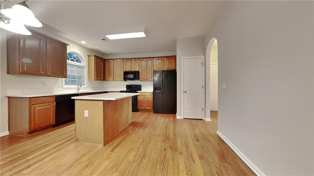 kitchen featuring sink, a center island, light hardwood / wood-style flooring, and black appliances