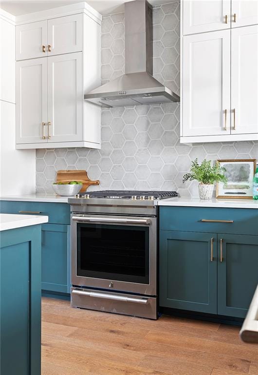 7220 Summit Pl, Alpharetta, GA 30009 - kitchen featuring wall chimney exhaust hood, gas stove, blue cabinetry, light countertops, and light wood-style flooring