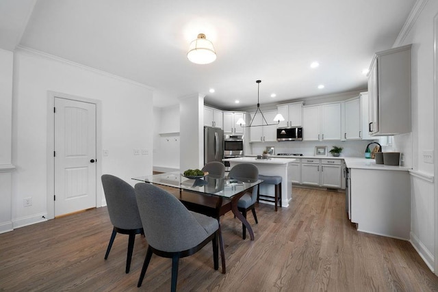 dining area featuring wood-type flooring, a notable chandelier, and crown molding