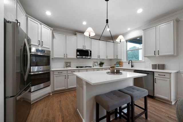 kitchen with hanging light fixtures, a center island, white cabinets, and appliances with stainless steel finishes