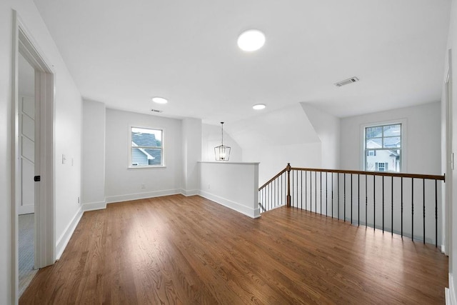 unfurnished room with wood-type flooring, a wealth of natural light, and a notable chandelier