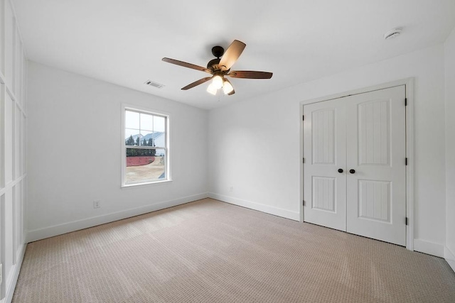 unfurnished bedroom featuring ceiling fan, light colored carpet, and a closet