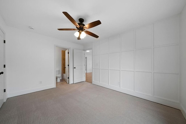 unfurnished bedroom featuring ceiling fan, light colored carpet, and ensuite bath