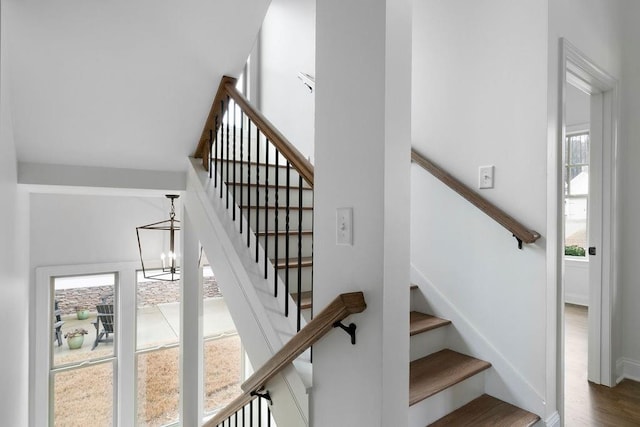 stairs with hardwood / wood-style floors and a chandelier