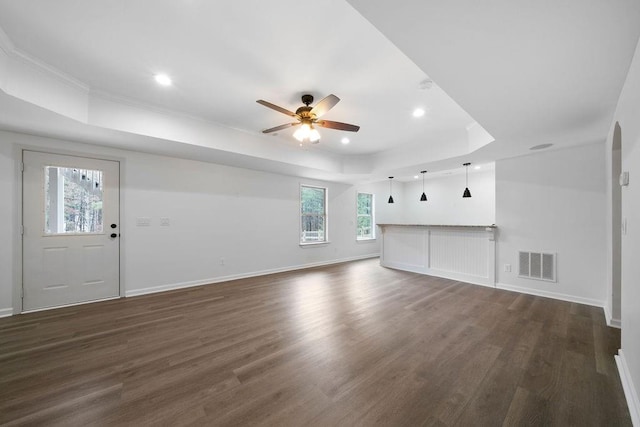 unfurnished living room featuring dark hardwood / wood-style floors, ceiling fan, and a tray ceiling