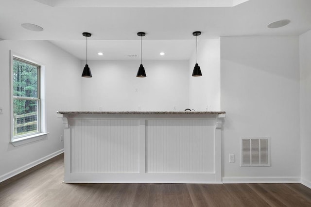 bar with pendant lighting, hardwood / wood-style floors, and light stone countertops